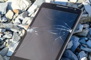 Frustrated phone on the rocks. Glass shattered on rocks on a sma photo