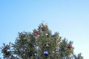 decoraciones nuevo año árbol. oropel y juguetes, pelotas y otro decoraciones en el Navidad Navidad árbol en pie en el abierto aire. foto