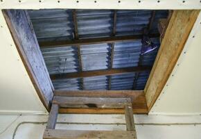 Open the entrance to the attic. The staircase and the door to the attic of the house photo