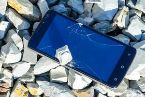 Frustrated phone on the rocks. Glass shattered on rocks on a sma photo