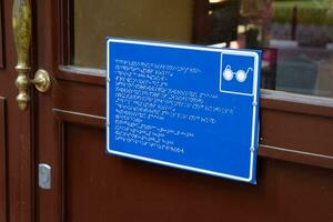 plate with a tongue for the blind on the doors of the building. photo