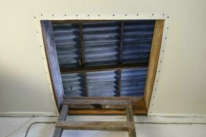 Open the entrance to the attic. The staircase and the door to the attic of the house photo