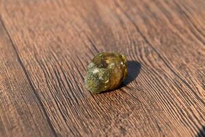 Stone of gallbladder. The result of gallstones. A calculus of dissimilar composition on a wooden background. photo