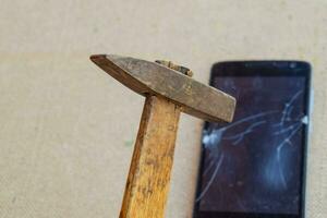 Hammer and smartphone. The screen of the smartphone, a broken ha photo