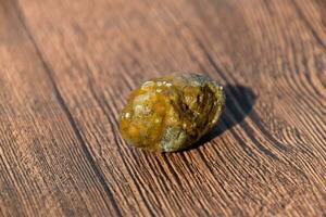 Stone of gallbladder. The result of gallstones. A calculus of dissimilar composition on a wooden background. photo