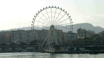 Ferris ruota Filatura con edifici di un' città a tramonto nel malaga, Spagna video