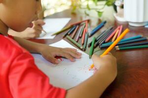 Asian boys are happy to draw their imaginations and paint with crayons in their spare time at home during school holidays. Soft and selective focus. photo