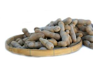 isolated basket of tamarind on a white background, which is a fruit with long pods Mature pods have a hard, crisp shell that breaks easily and is brown. The inside becomes brown and covers the seeds. photo