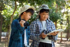 Asian boy and friends Invite each other to see birds in the community forest on holidays. And help each other to search for the types of birds found from the birds Guide book. photo