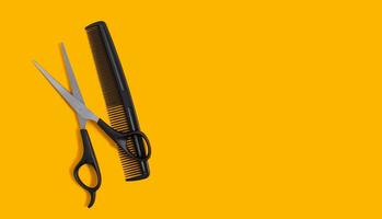 Barber scissors and a comb on a yellow background. Hair salon concept. Copy space. View from above. photo