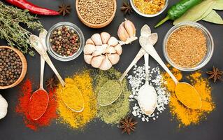 A variety of spices and herbs on a dark table. Cooking background. View from above. Ingredients for cooking. Table background menu. photo