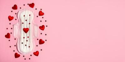 Sanitary napkin in red sequins on a pink background. Concept of female menstruation. Critical days of women, gynecological menstrual cycle. Banner. Copy space. photo