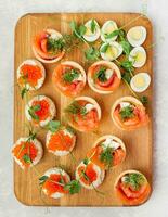 Appetizer and tartlets with red fish on the board. Festive snack. Menu for the festive table. View from above. photo