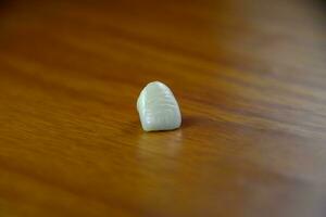 Tooth, metal ceramic crown on the table. Denture made of metal ceramics photo