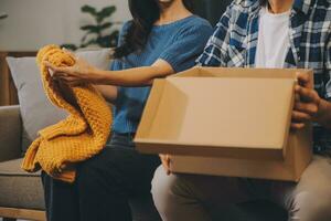 Two Asian blogger showing clothes in front of the camera to recording vlog video live streaming at her shop. Online Shopping Cart notion. on sofa at home photo