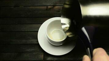 scrosciante caffè a partire dal un' caffè pentola in un' tazza su un' di legno sfondo video
