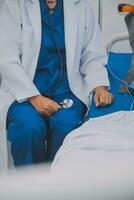 Asian Doctor make routine health check with patient in hospital ward photo