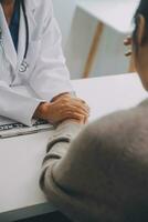 médico y paciente sentado cerca cada otro a el mesa en clínica oficina. el atención es en hembra médico manos tranquilizador mujer, solamente manos, cerca arriba. medicina concepto foto