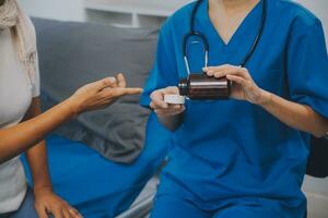 asiático mujer enfermero participación un medicina botella y narración información a asiático mayor mujer antes de administrar medicamento. cuidador visitar a hogar. hogar salud cuidado y enfermería hogar concepto. foto