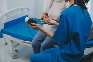 Asian woman nurse holding a medicine bottle and telling information to Asian senior woman before administering medication. Caregiver visit at home. Home health care and nursing home concept. photo