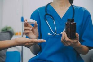 Asian woman nurse holding a medicine bottle and telling information to Asian senior woman before administering medication. Caregiver visit at home. Home health care and nursing home concept. photo