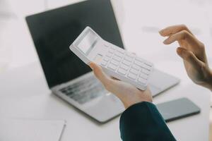 Businessman using a calculator to calculate numbers on a company's financial documents, he is analyzing historical financial data to plan how to grow the company. Financial concept. photo