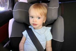 2 year old girl sits in Car Seat. A cute blond caucasian todler photo