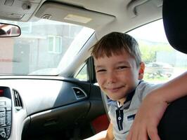 The boy is sitting in the front seat of the car. Close-up portrait. photo