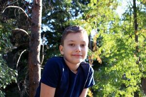 Portrait of a 9 year old blond boy in an autumn park. Handsome caucasian boy with big eyes looks into the camera. photo