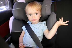 2 year old girl sits in Car Seat. A cute blond caucasian todler photo