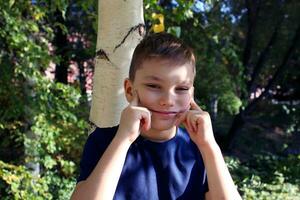 Portrait of a 9 year old blond boy in an autumn park. Handsome caucasian boy with big eyes looks into the camera. photo