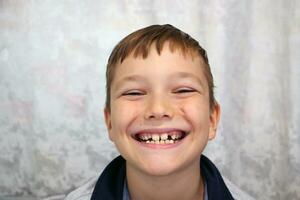 Boy smiles and shows his teeth. Close-up portrait. photo