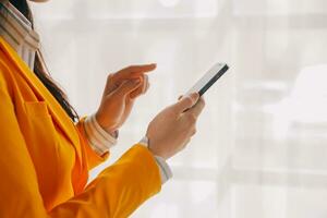 Young smiling business woman using smartphone near computer in office, copy space photo