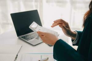 Businessman using a calculator to calculate numbers on a company's financial documents, he is analyzing historical financial data to plan how to grow the company. Financial concept. photo