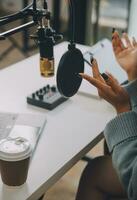 Woman recording a podcast on her laptop computer with headphones and a microscope. Female podcaster making audio podcast from her home studio. photo