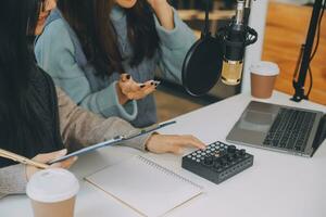 Woman recording a podcast on her laptop computer with headphones and a microscope. Female podcaster making audio podcast from her home studio. photo