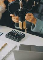 Woman recording a podcast on her laptop computer with headphones and a microscope. Female podcaster making audio podcast from her home studio. photo