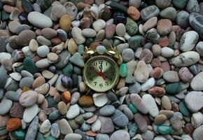 Vintage clock lies on a small sea pebbles and shells photo