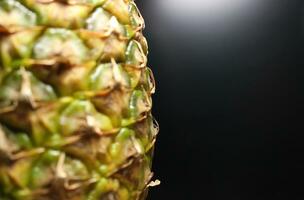 Soft focus side of juicy pineapple on a black background illuminated from the side photo