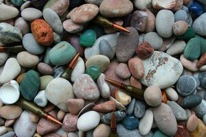 Bullets For a Gun Under Smooth Colored Stones And Seashells Texture Backgrounds photo