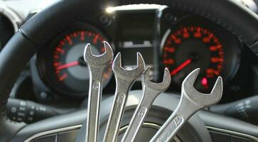 Four Different Size Chrome Spanners In Front Of Defocused Instrument Cluster With Red Backlight photo