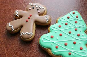 Holidays Background With Gingerbread Man And Pine Tree Cookies With Colored Icing On Leather Folder Closeup Angle View photo