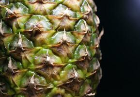 The knobby surface of a whole pineapple on the edge of the image photo