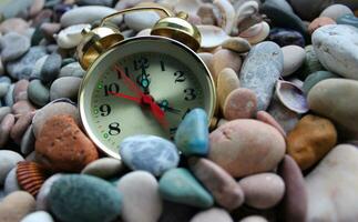 Rare clock with bells sprinkled with small pebbles on the seashore photo