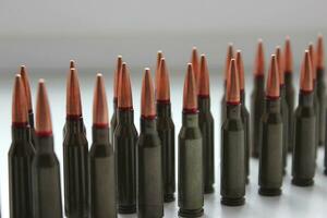 Live ammunition for assault rifle with red mark on a bullets in a row on white surface detailed side view stock photo