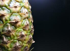 Ripe pineapple fruit close up isolated on a black background photo