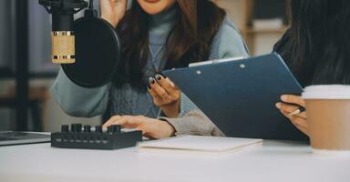 Woman recording a podcast on her laptop computer with headphones and a microscope. Female podcaster making audio podcast from her home studio. photo