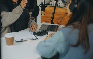 Woman recording a podcast on her laptop computer with headphones and a microscope. Female podcaster making audio podcast from her home studio. photo