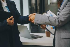 Real estate broker agent and customer shaking hands after signing contract documents for realty purchase, Bank employees congratulate, Concept mortgage loan approval. photo