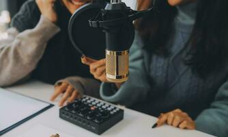 Woman recording a podcast on her laptop computer with headphones and a microscope. Female podcaster making audio podcast from her home studio. photo